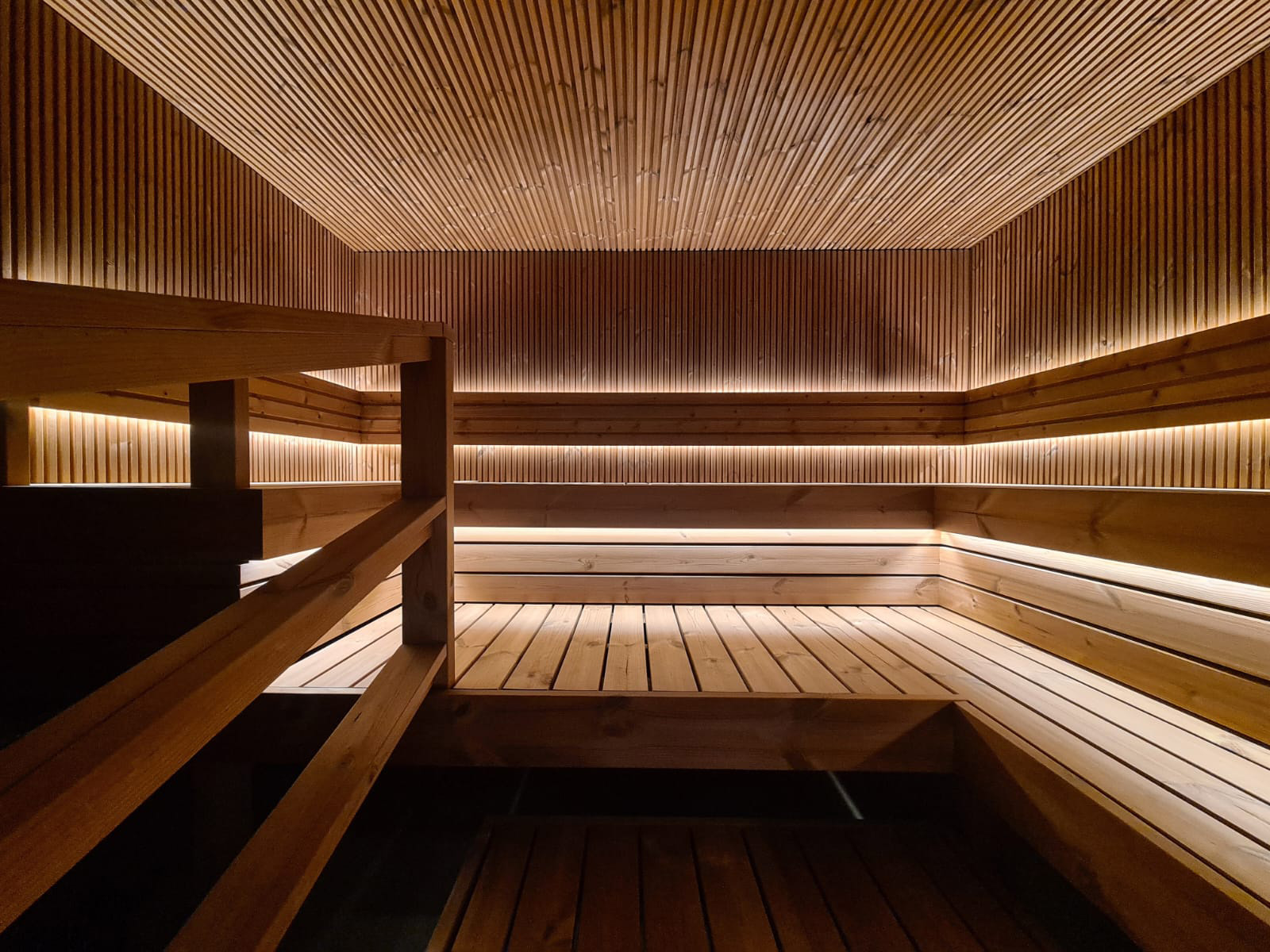Wood-lined sauna interior with a slatted ceiling and tiered benches